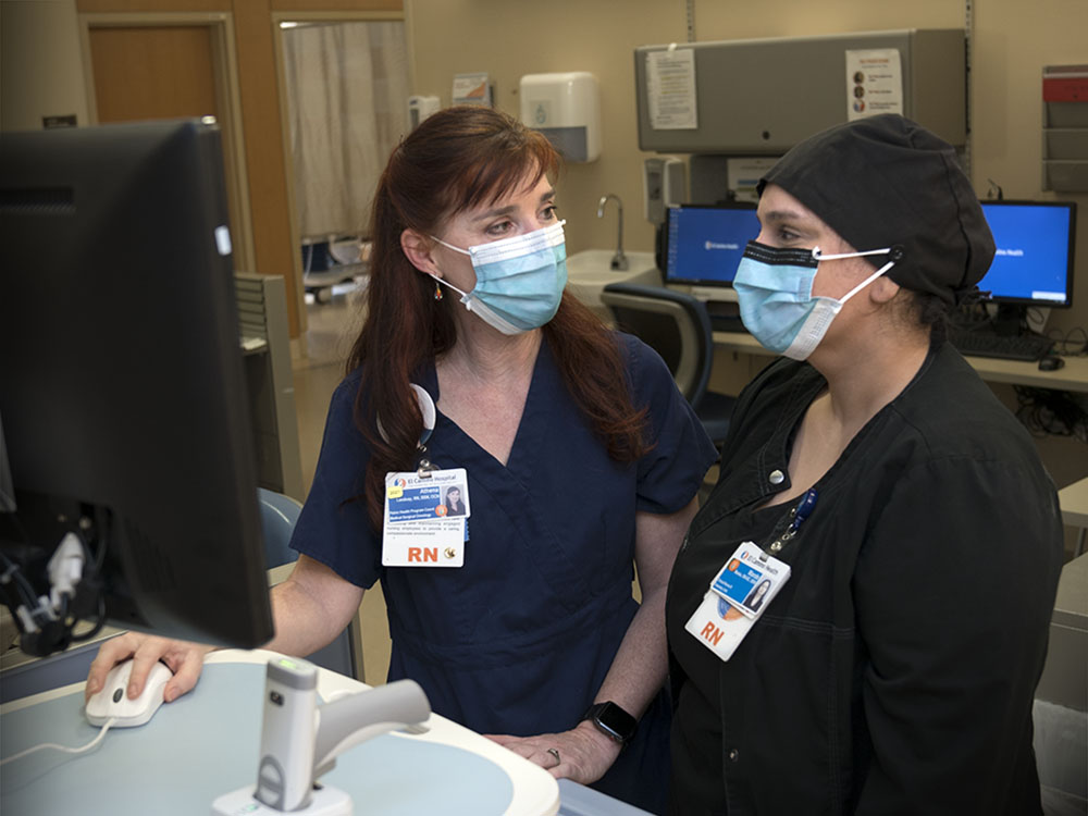 Nurses at computer station having a conversation