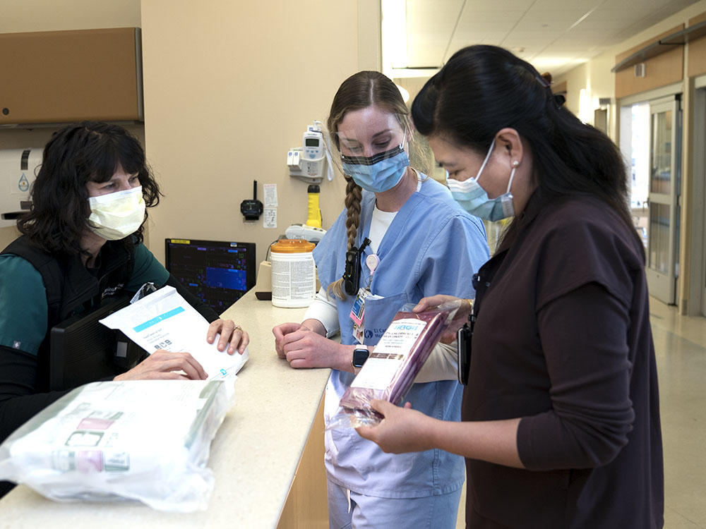 Nurse talking together over notes at nurse station