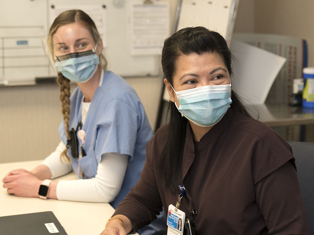 Two nurses with masks on looking over beyond frame possibly at a teacher