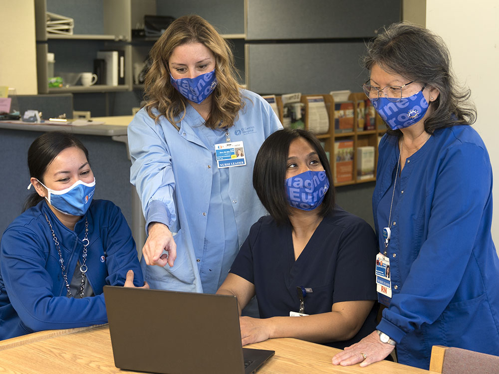 Nurse talking together over notes at nurse station