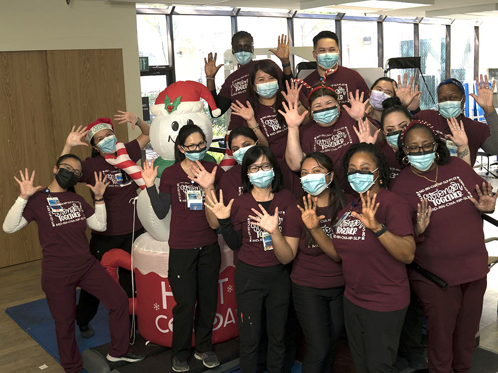 A group of nurses with their hands in the air and masks on