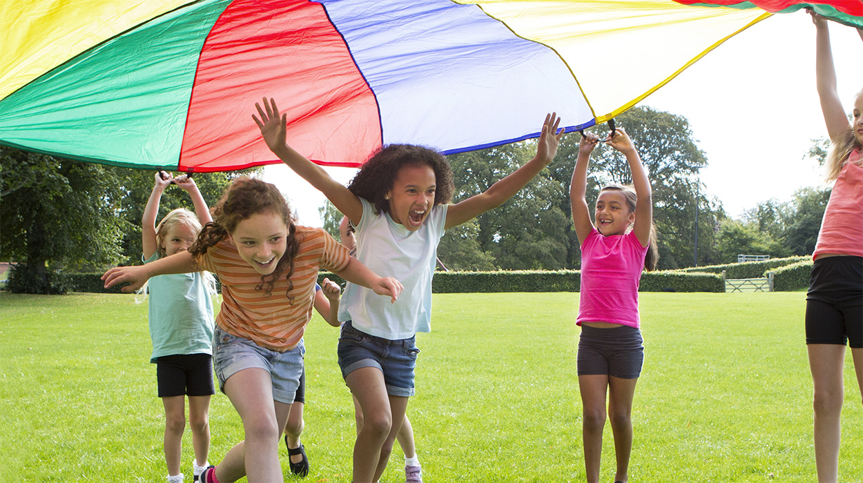 Children playing under colorful parachute