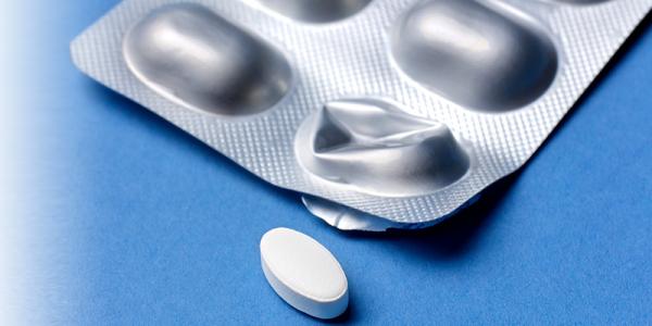 Single White Pill on Blue Surface Beside Blister Pack with Empty Slot