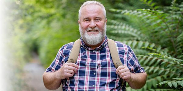 Elderly Man Enjoying a Forest Walk Wearing a Backpack and Smiling Elderly Man Enjoying a Forest Walk Wearing a Backpack and Smiling