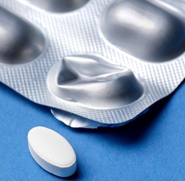 Single White Pill on Blue Surface Beside Blister Pack with Empty Slot